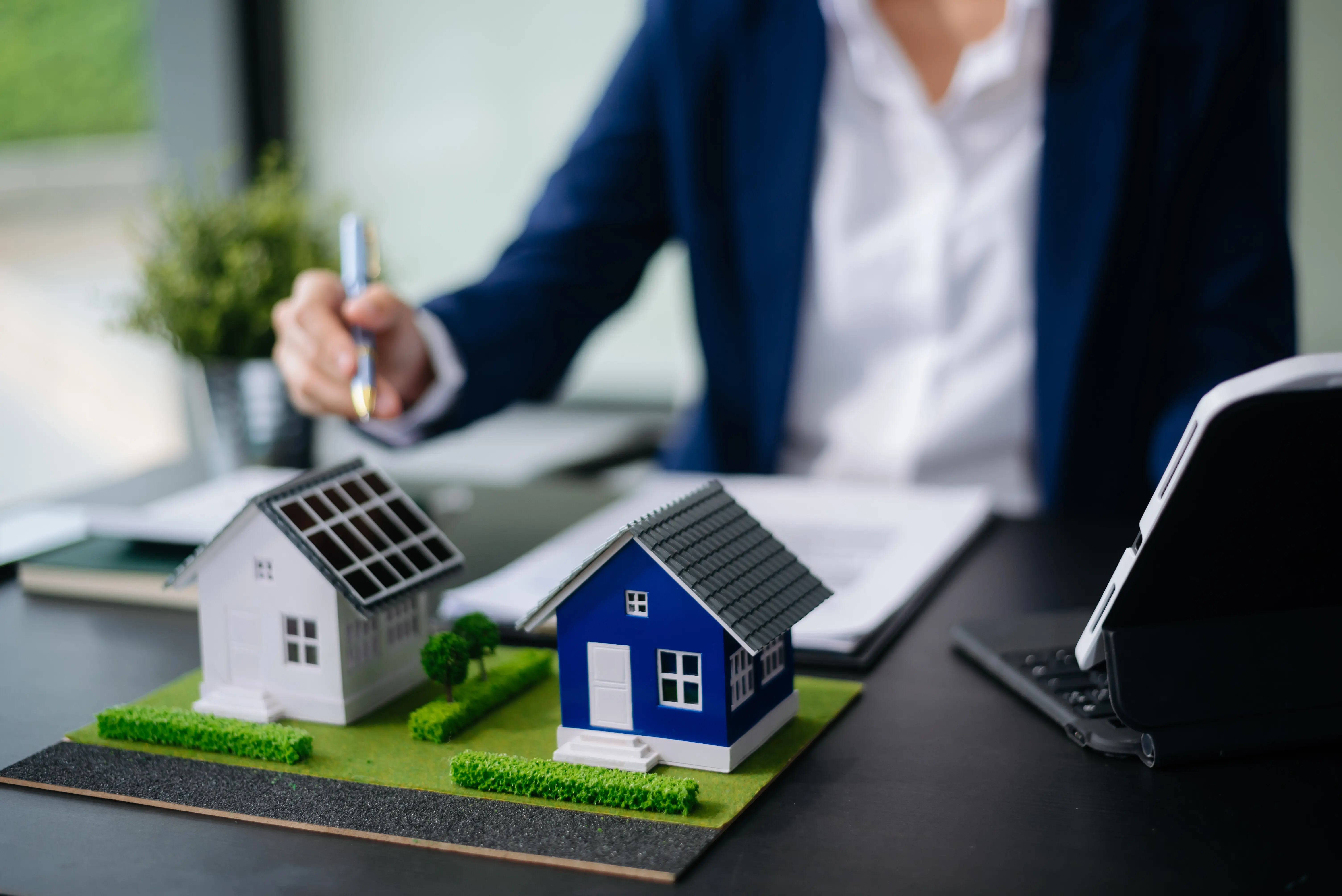 Balance im Immobiliensektor: Der Immobilienmakler erklärt den Hausstil, zeigt das Hausdesign und den Kaufvertrag; Modellhaus und Eigentumswohnung.