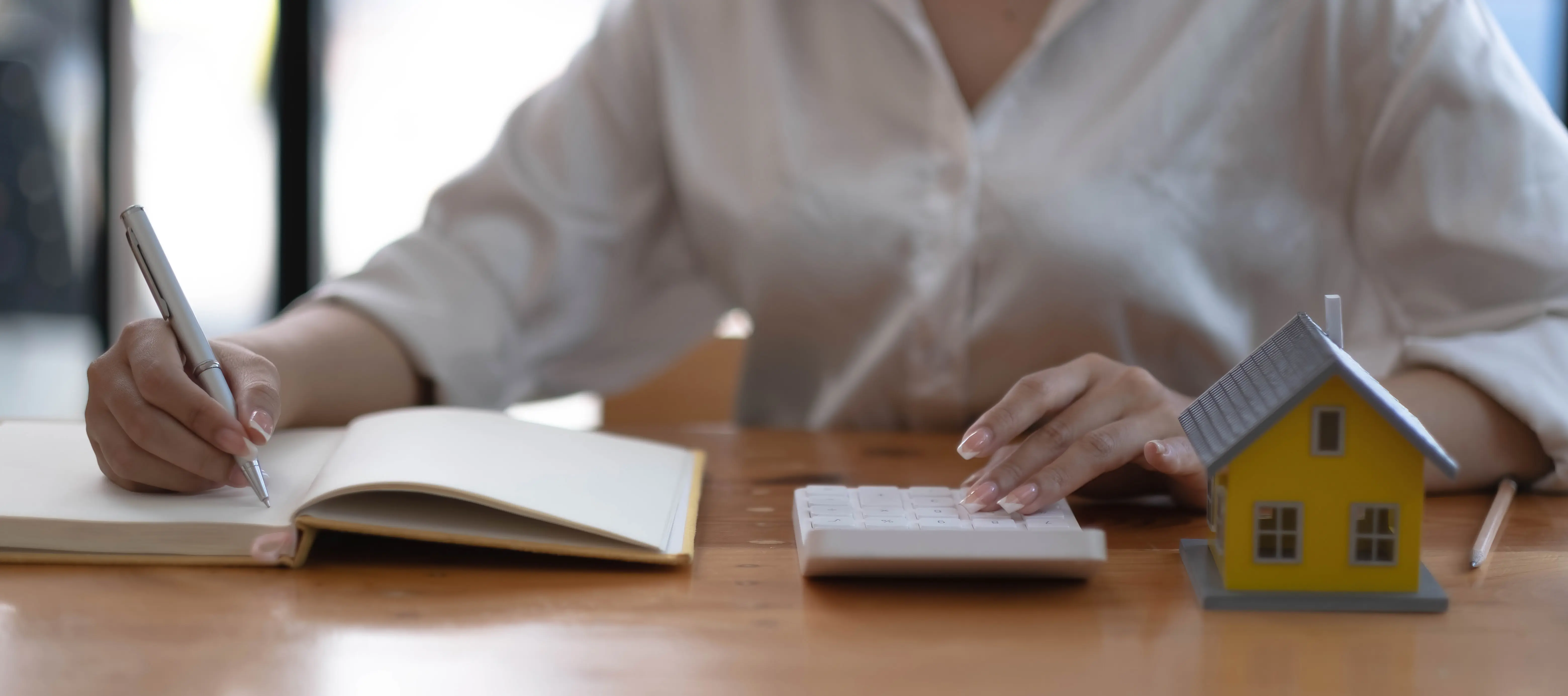 Verkauf eines Hauses mit Versicherung: Ein Verkäufer oder Immobilienmakler berechnet den Preis, um eine Sonderaktion sowie eine kostenlose Versicherung für Kunden anzubieten, die ein Musterhaus kaufen.